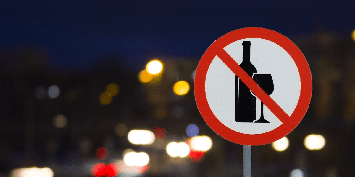 A sign with a wine bottle and glass struck through with a red line, indicating that no alcohol is allowed. 